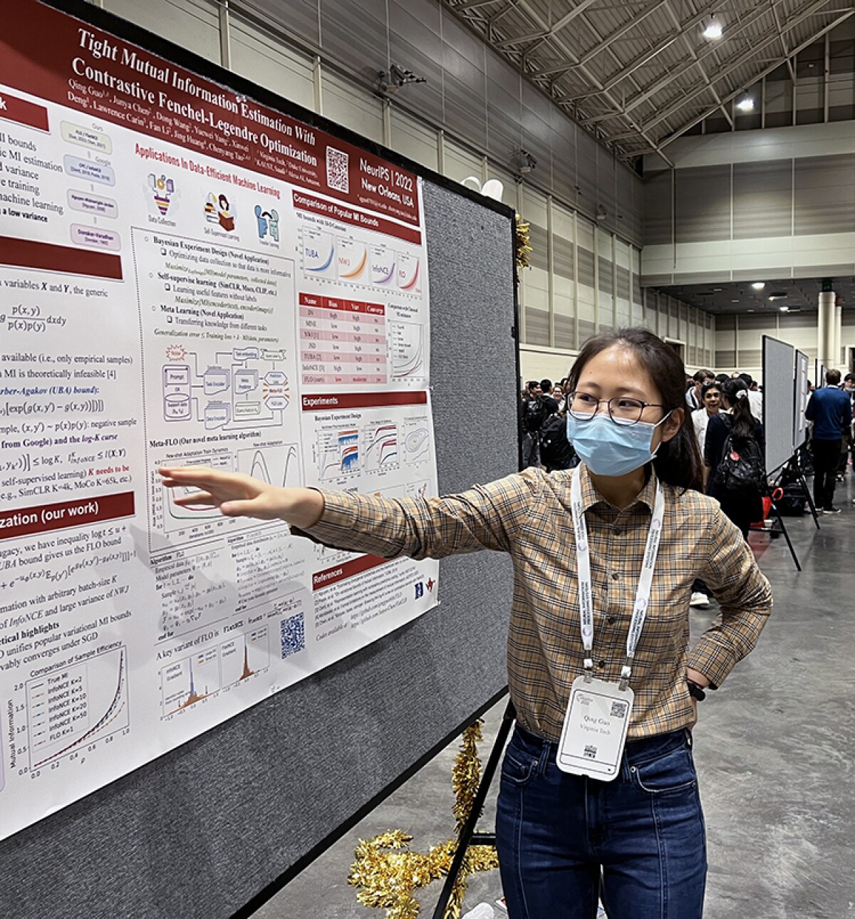 Qing Guo, wearing a mask, is seen presenting a research poster