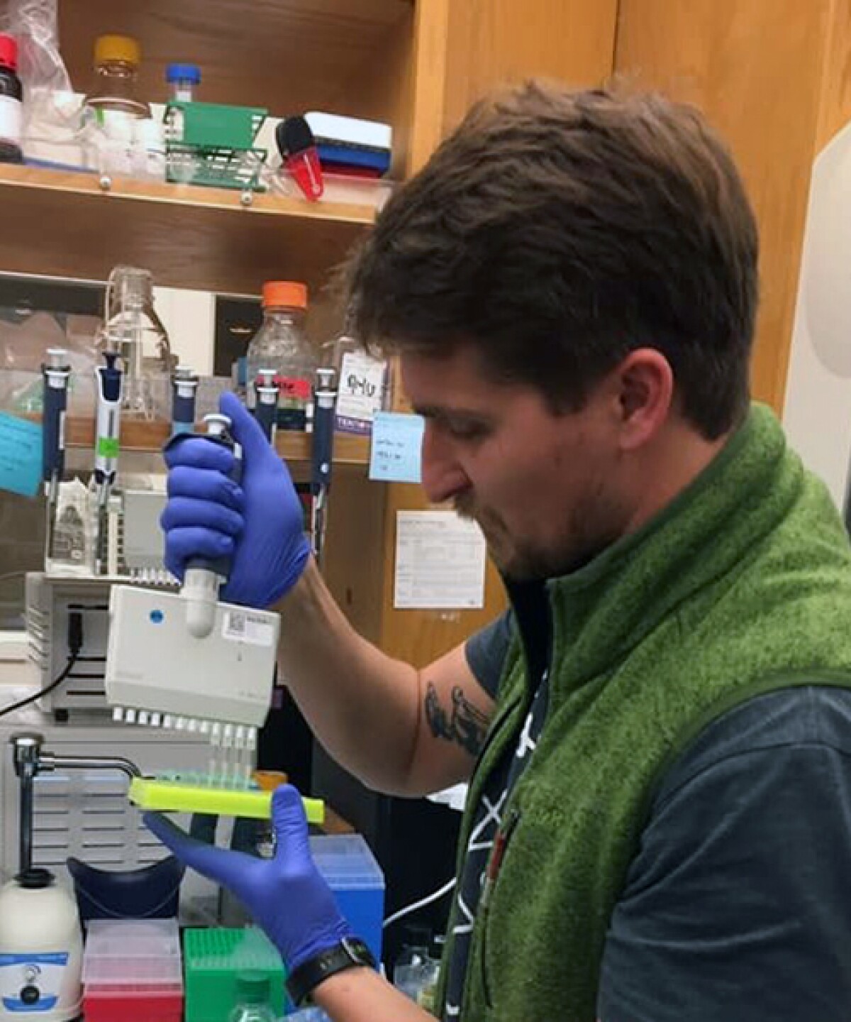 Sergey Menis is seen in a lab setting, wearing gloves while holding a device