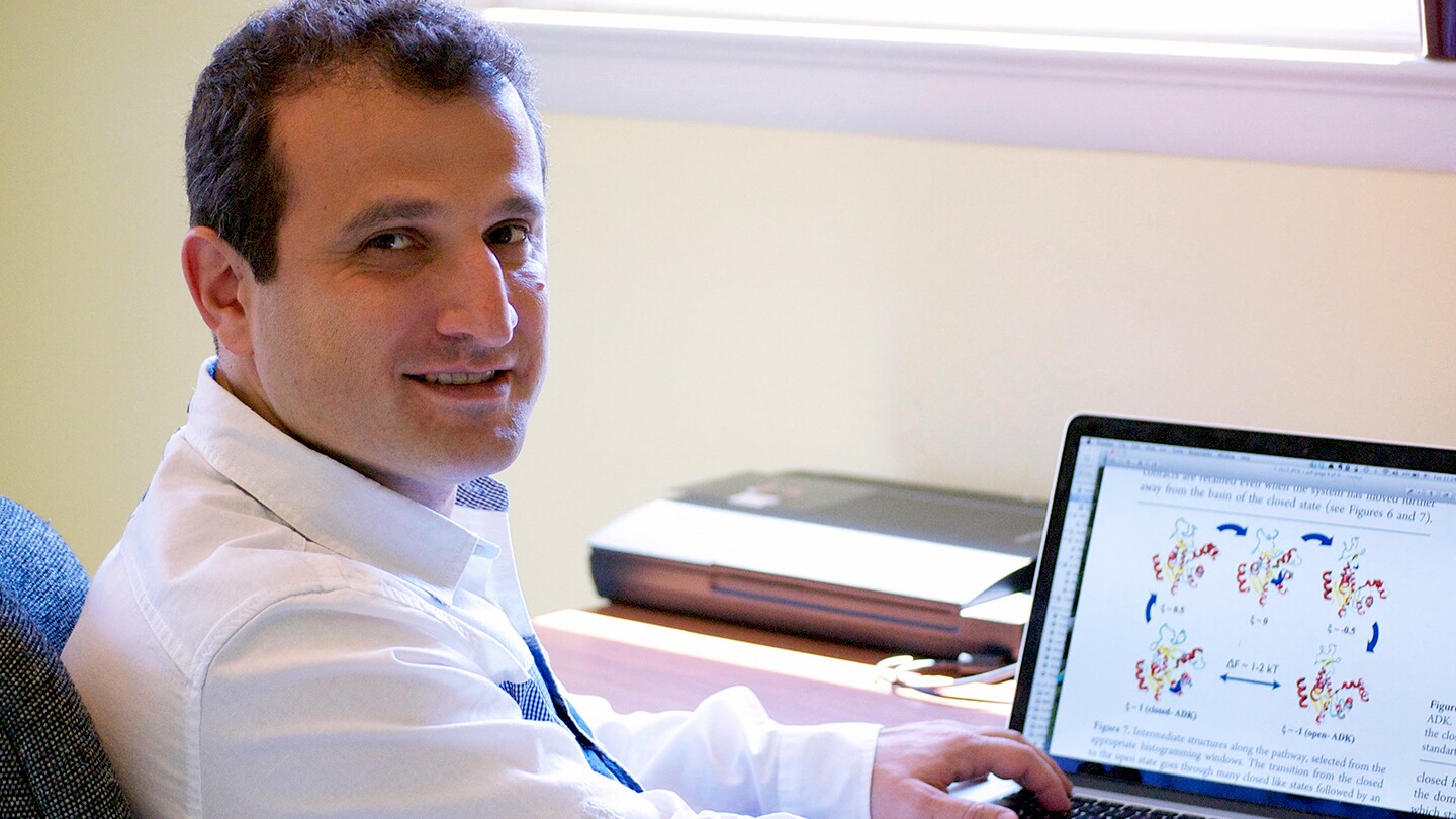 Garegin Papoian, the Monroe Martin Professor at the University of Maryland, is seen sitting at a desk with an open laptop in front of him. He has turned around in his seat to face the camera.