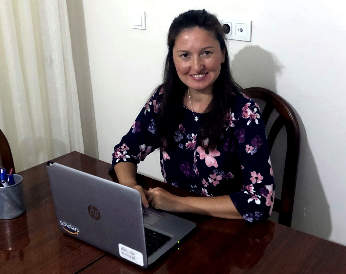 Emine Yilmaz, an Amazon scientist, sitting at a table with an open laptop in front of her.