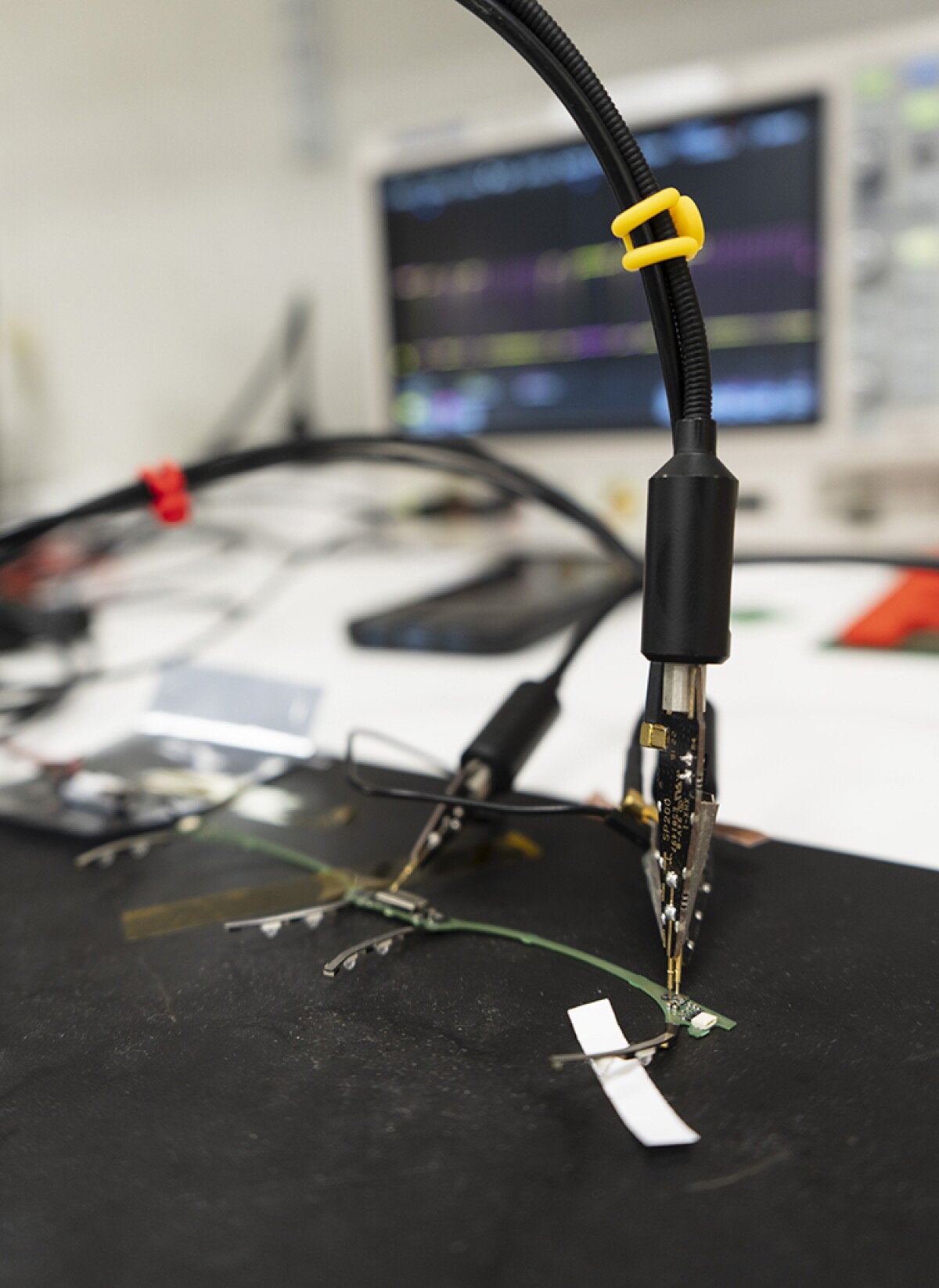 Some electrical clamps and wires are seen in the foreground with a computer screen in the background