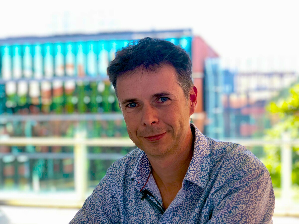 Anton van den Hengel is seen smiling into the camera, with some office buildings in the background