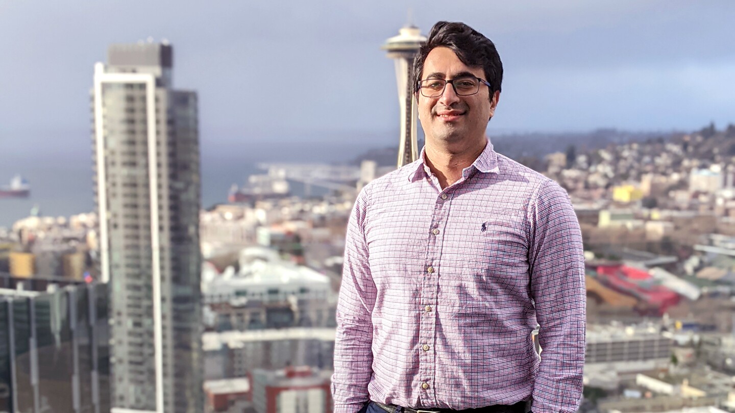 senior applied science manager Ali Dashti stands outside with a cityscape in the background