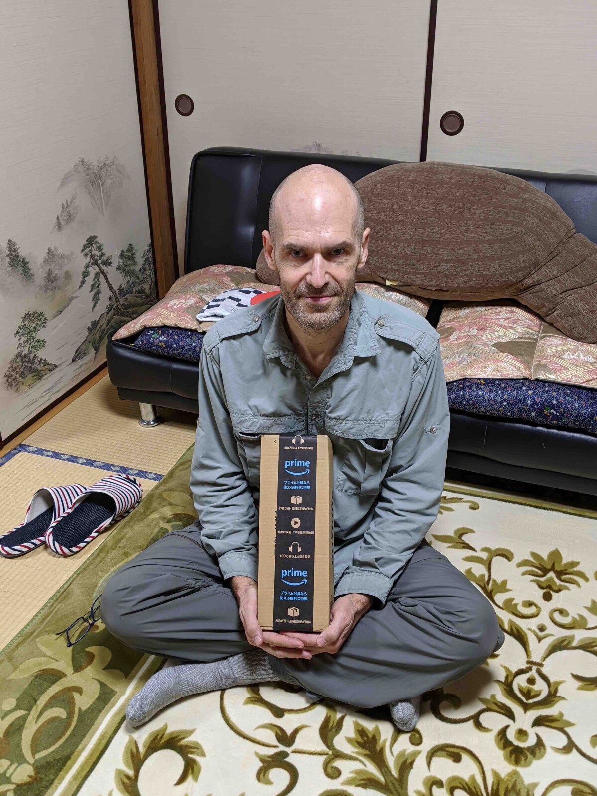 Dean Foster, an economist who works on optimizing Amazon's supply chain technologies, is seen holding an Amazon package he ordered from the middle of a forest in Japan.