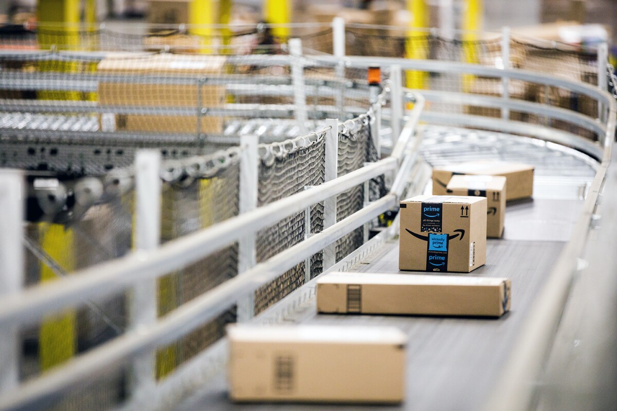 Amazon packages, one with a visible Prime logo, travel along a conveyor belt