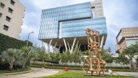 A rear view of Amazon's second office building in Bangalore, India, featuring a geometric sculpture and lush greenery
