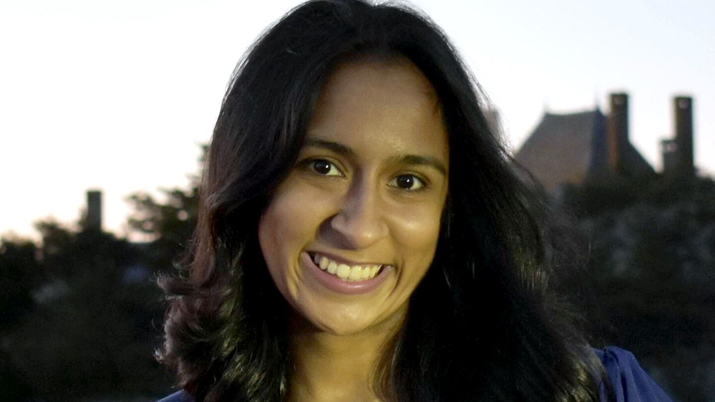 Maryam Aziz is seen standing outside, smiling into the camera