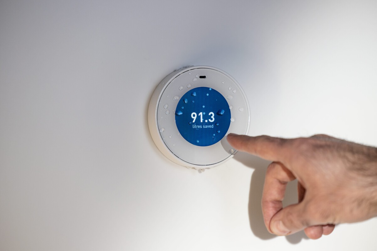 An Orbital Shower control dial with a digital reading showing 91.3 liters saved is seen, a person's hand is seen is pointing to the dial