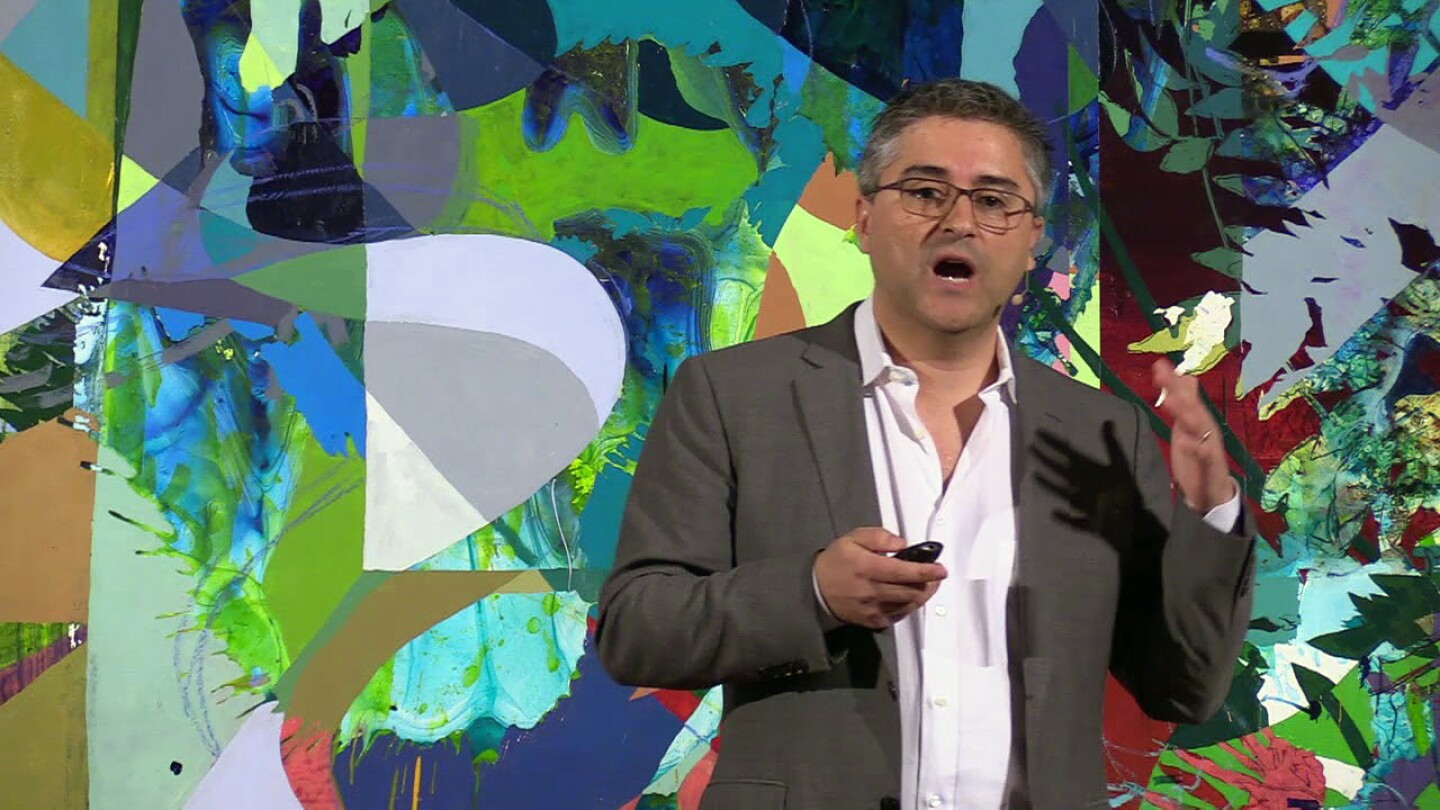 René Vidal, an Amazon Scholar who is also the Herschel Seder Professor of Biomedical Engineering and director of the Mathematical Institute for Data Science at Johns Hopkins University, is seen giving a talk against a background of an abstract painting.