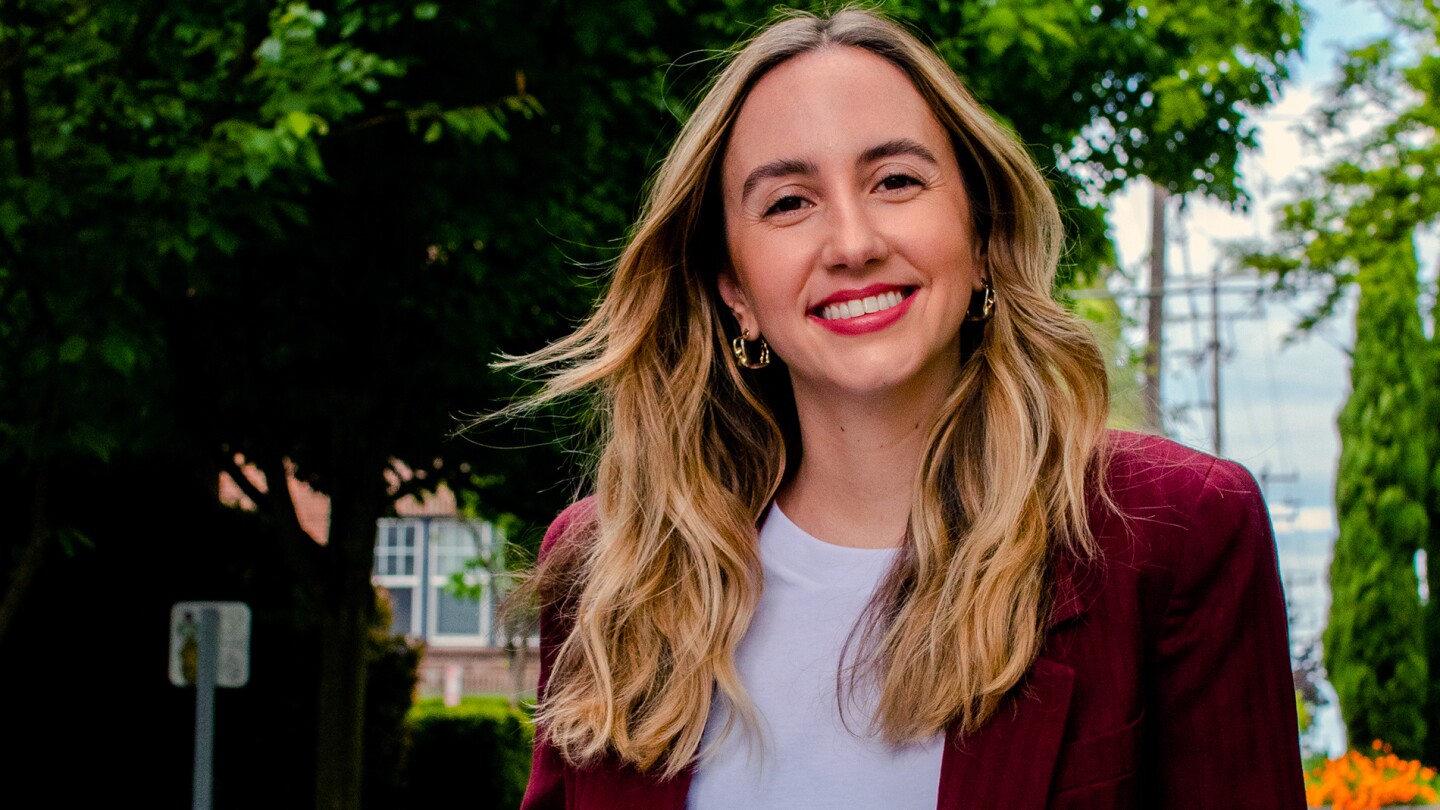 Image shows Cristiana Lara, a research scientist, standing outside and smiling with a tree in the background