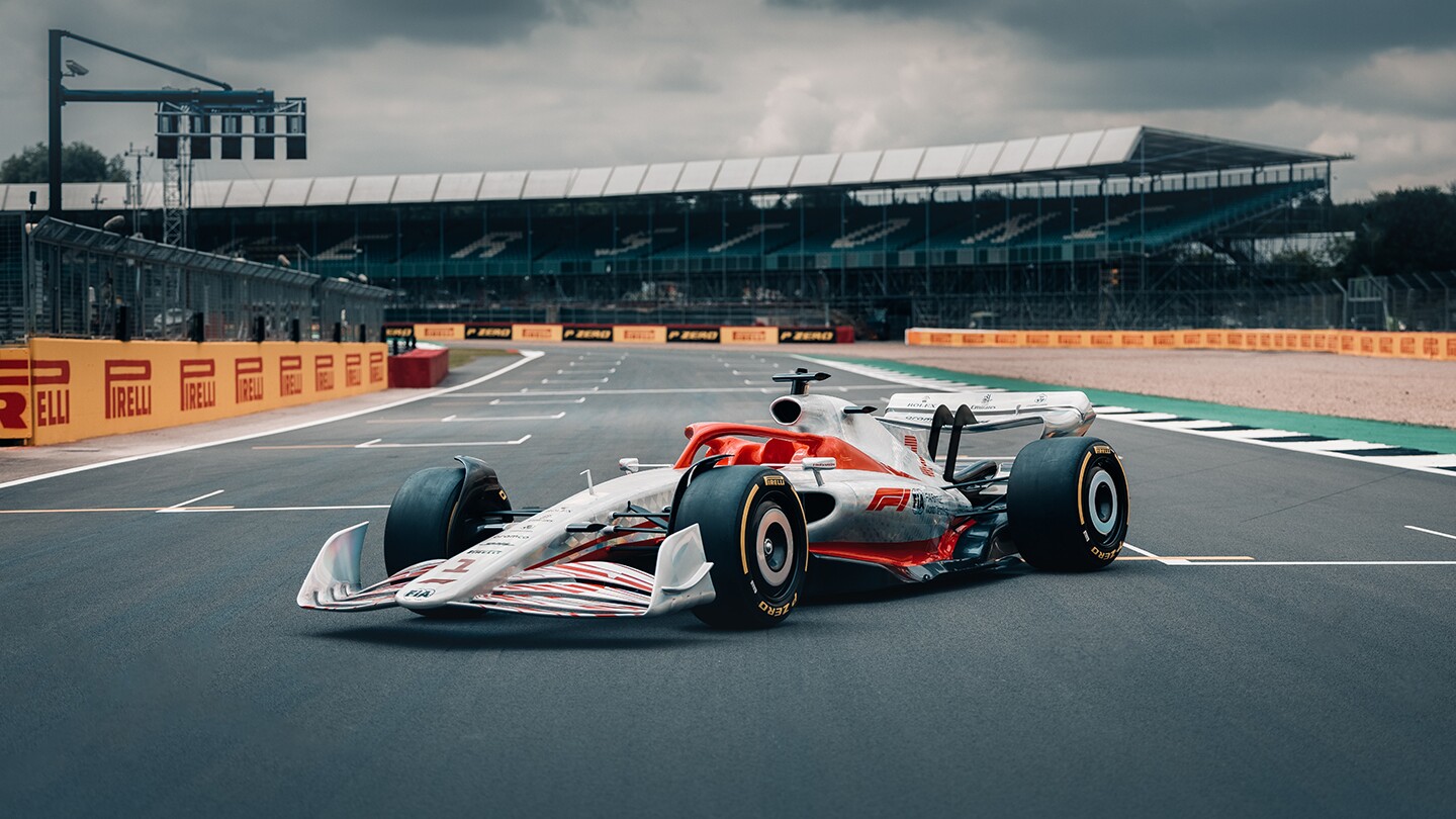 Image shows the 2022 F1 car sitting in profile on a racetrack with viewing stands in the background