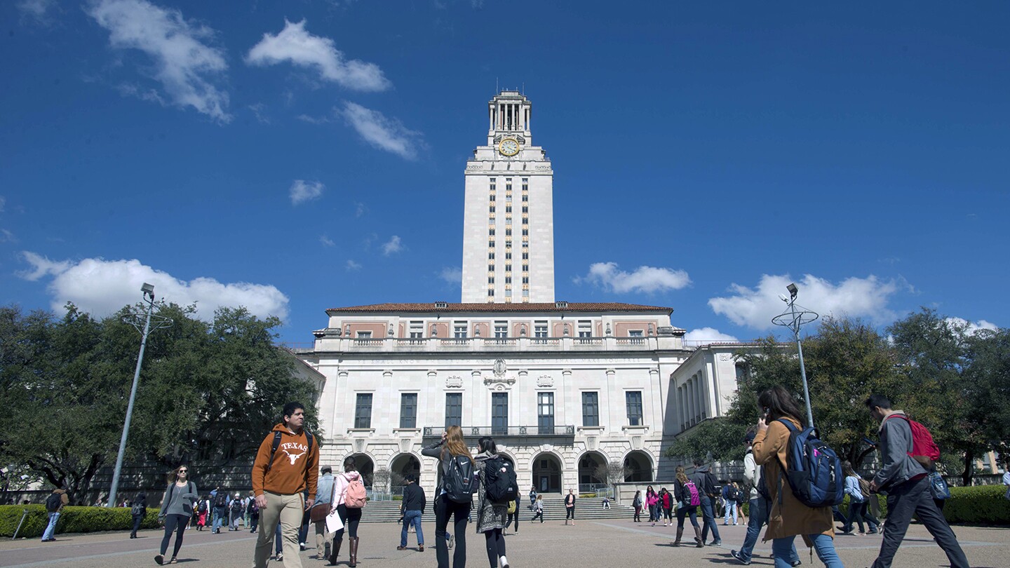 UT Austin campus tower is seen on a sunny day, there are students walking in the foreground