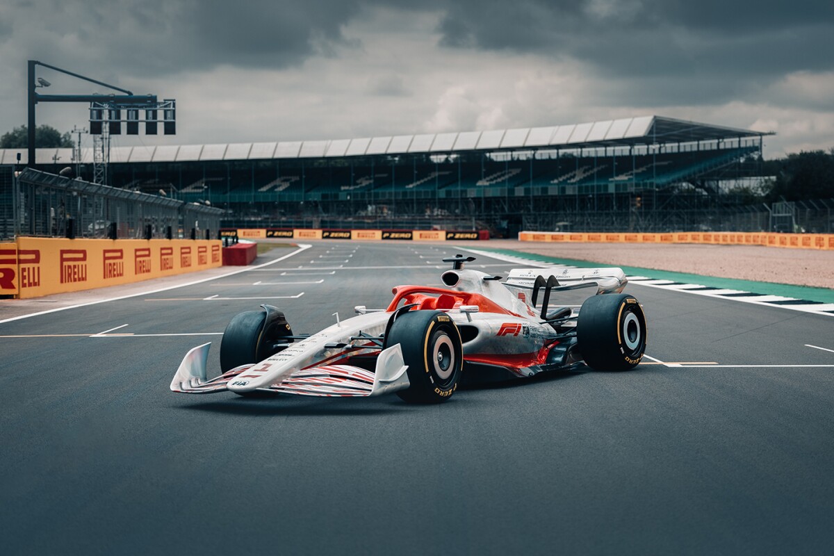 Image shows the 2022 F1 car sitting in profile on a racetrack with viewing stands in the background
