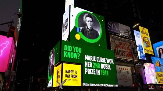 To mark Pi Day this year, Amazon Science is utilizing a Times Square billboard normally used by Amazon Music to honor scientists, engineers, and mathematicians past, present, and future. This is an image of the Marie Curie part of the billboard display.