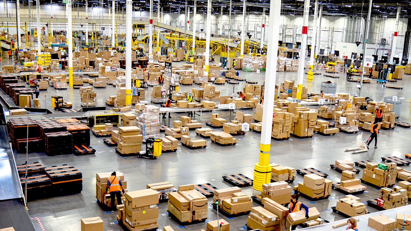 An overhead image shows a fulfillment center with boxes and conveyor belts in a large, open facility