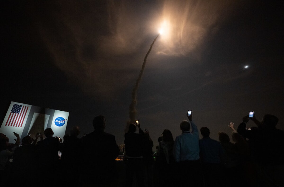Guests watch the launch of NASA’s Space Launch System rocket carrying the Orion spacecraft on the Artemis I flight test, Wednesday, Nov. 16, 2022, from Operations and Support Building II at NASA’s Kennedy Space Center in Florida. NASA’s Artemis I flight test is the first integrated flight test of the agency’s deep space exploration systems: the Orion spacecraft, Space Launch System (SLS) rocket, and ground systems. SLS and Orion launched at 1:47 a.m. EST, from Launch Pad 39B at the Kennedy Space Center. The Moon is in the upper right.