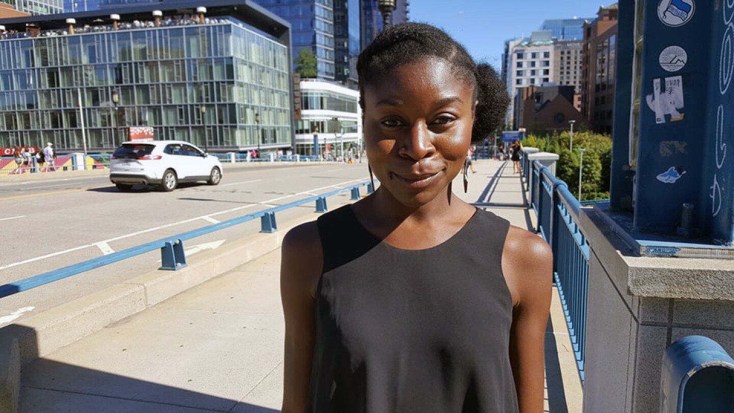 Erica Aduh, a research scientist, is seen standing outside with office buildings in the background