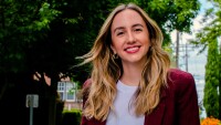 Image shows Cristiana Lara, a research scientist, standing outside and smiling with a tree in the background
