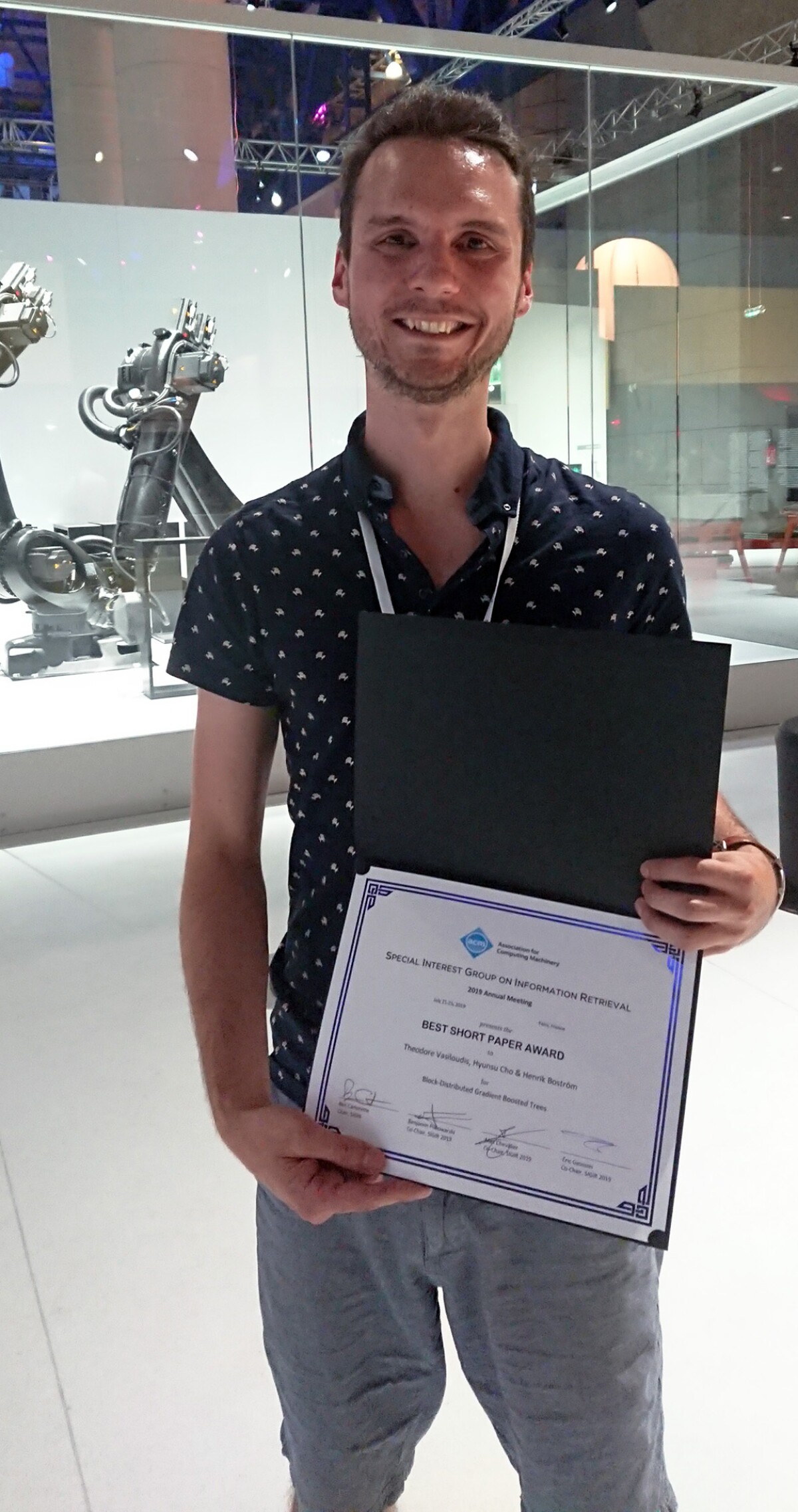Theodore Vasiloudis poses with the publication that won the best short paper award at SIGIR 2019.