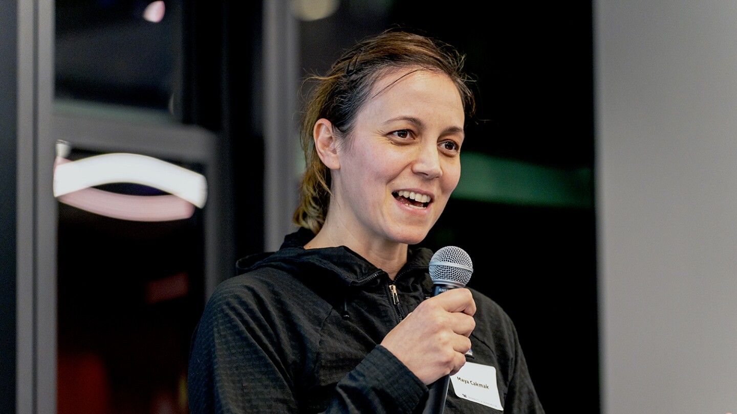 Maya Cakmak, an associate professor at the University of Washington, is seen speaking at an Amazon event, she is holding a mic while giving a talk