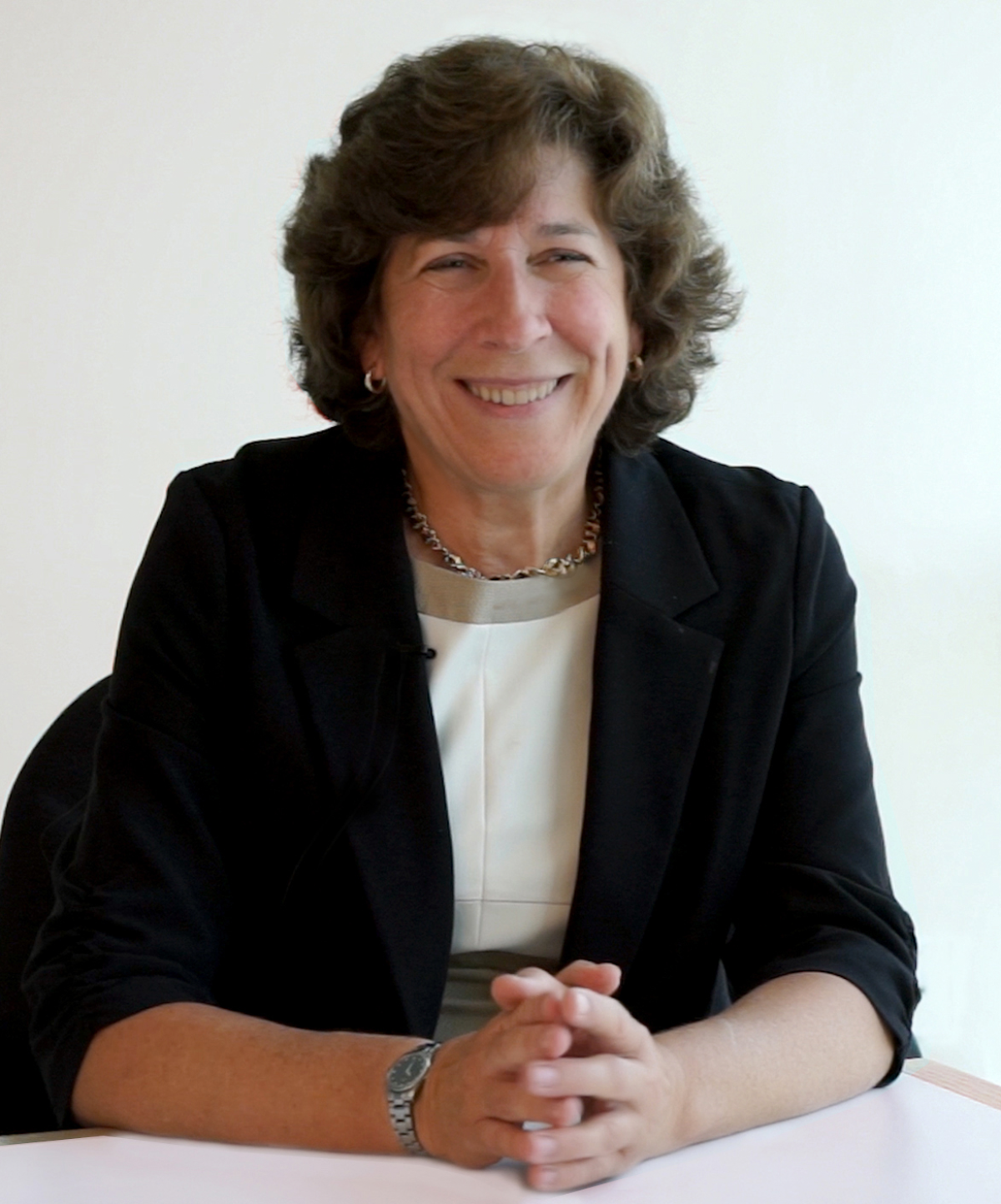 Portrait of McKeown from the waist up, in a business suit, seated at a desk with her hands clasped in front of her.